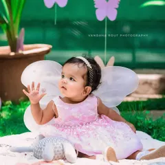 A magical moment for this little butterfly fairy. Dressed in a sparkling pink dress with delicate wings, she looks enchanting in this outdoor garden setting.