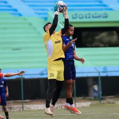 A goalkeeper leaps high to make a confident catch, showcasing the excellent training and bravery of our young players.