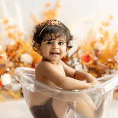 Making a statement with her eyes! This little one is loving her bubbly bath, surrounded by beautiful autumn-colored flowers.