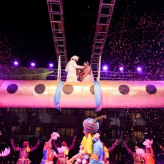 A truly unique Varmala entry, with the couple elevated on a platform designed like a giant flute (bansuri), a nod to a Krishna-themed celebration. Dancers with peacock feathers celebrate below.