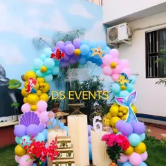 An underwater adventure with this Little Mermaid theme. I used a palette of ocean blues, purples, and yellows to create a balloon arch decorated with character cutouts like Ariel, Flounder, and Sebastian for an outdoor party.
