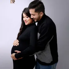 An intimate and classic maternity pose. The couple is dressed in black, creating a timeless look that puts all the focus on their connection and the baby bump.
