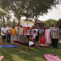 A happy group photo from our 2019 park event. I'm demonstrating Mayurasana to show what's possible with practice, surrounded by smiling faces.