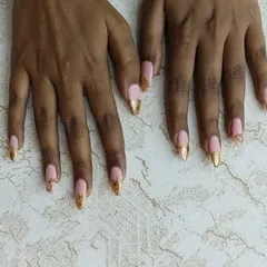 Glamour at your fingertips. This custom design on gel extensions combines a soft pink base with sparkling gold glitter tips and delicate stone accents for a truly luxurious and eye-catching look.