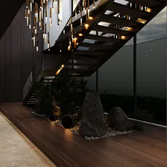 The dark wood of the staircase and wall paneling creates a moody and sophisticated backdrop for the indoor garden. The warm, integrated lighting highlights the textures of the rocks and plants, making it a captivating feature day and night.