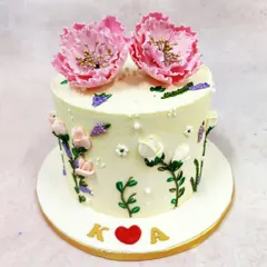 We paint a picture of romance with this hand-painted flower cake. Delicate pink blooms, resembling peonies, crown the cake, while smaller blossoms and leaves are artfully painted onto the buttercream, creating a piece of edible art for an intimate celebration.