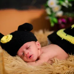 This little one is buzzing in their dreams. A close-up of a newborn in a hand-knitted bee costume, sleeping peacefully in a rustic wooden crib.