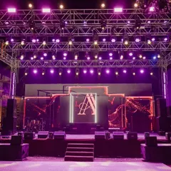 The concert-style stage setup for the Sangeet night. The powerful lighting rig and large LED screen with the couple's monogram ensured a high-energy, unforgettable party.