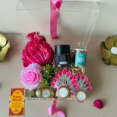 Our exquisite acrylic box offers a modern and chic presentation. It's filled with festive goodies like Ferrero Rocher, a pink potli, and peacock-themed diyas.