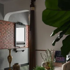 First impressions matter, and the foyer of our 'Kaalam' project sets a tone of rooted tradition. A reclaimed wooden sthamba (pillar) stands as a proud centerpiece, complemented by the rustic texture of an exposed brick wall and a vintage-inspired mirror. This entry is a deliberate nod to the past, reinterpreted for a modern home.