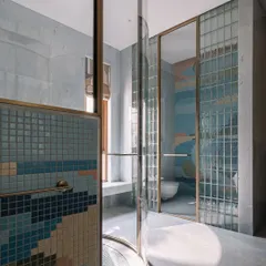 We believe bathrooms should be an escape. This master bathroom features a unique cylindrical shower cubicle, where a playful dance of colorful mosaic tiles and glass blocks creates a space that feels both luxurious and deeply personal.