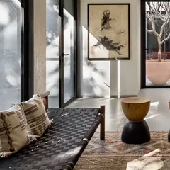 A quiet seating nook in the Mango Orchard House, positioned to overlook both the garden and an internal courtyard. The woven bench and wooden stools emphasize the connection to natural materials.