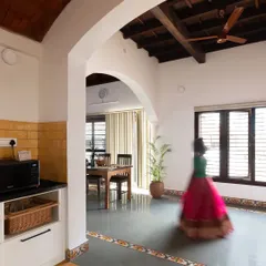 The interior of the Basavanagudi house, showing the seamless flow from the kitchen to the dining area. The archway and exposed beam ceiling add traditional character to the open-plan space.