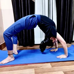 A student demonstrates a beautiful Chakrasana (Wheel Pose). This deep backbend is excellent for spinal flexibility, strengthening the arms and legs, and opening the chest to improve breathing.