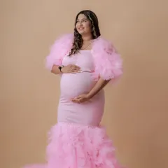 A beautiful full-length shot of a mom-to-be in a stunning pink mermaid-style gown with a dramatic ruffled train.