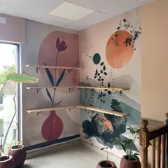 This abstract mural uses soothing colors and simple shapes like vases and botanicals. It was installed on a corner wall, creating a continuous piece of modern art that enhances the space.