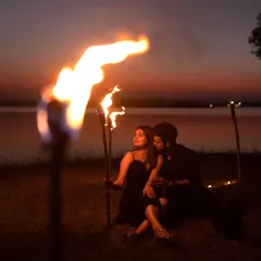 Creating a dramatic and romantic atmosphere with fire torches during a sunset pre-wedding shoot by the lake. This is for couples who want bold, unforgettable images.