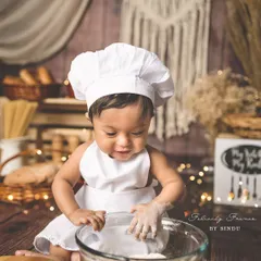 This little chef is busy making some delicious memories. The rustic kitchen setup and messy flour make for a fun and interactive photoshoot.