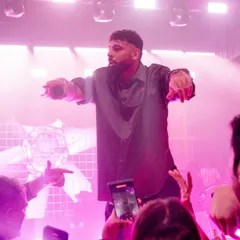 We curate and manage top talent to match the energy of your event. Here, a headline artist engages with the crowd, creating an unforgettable concert atmosphere during a grand Sangeet celebration.