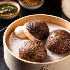 Another look at our Mushroom Bao Buns, served in a traditional bamboo steamer with a selection of dipping sauces, ready to be enjoyed.