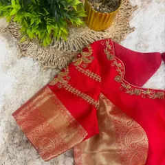 This view highlights the combination of rich red fabric and shimmering gold brocade on the sleeves of a designer blouse, a classic choice for South Indian bridal wear.