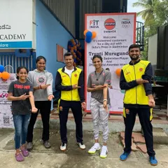 Our students and coaches pointing to the Fit India logo during an event with IndianOil, joined by professional badminton player Trupti Murgunde.