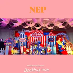 A wide view of the detailed carnival stage setup, showcasing multiple themed props like a life-sized giraffe, circus signs, and colorful balloon arrangements.