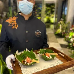 A server holds a tray with appetizers served in natural leaf bowls. This eco-friendly and stylish presentation is perfect for outdoor or rustic-themed weddings, showcasing our attention to detail.