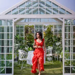 A beautiful shot of the red co-ord set in a greenhouse setting, showing its versatility for different photoshoot locations.
