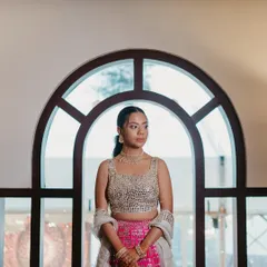 A portrait of the bride against an arched window. Her natural, skin-like makeup looks flawless in the soft light, paired with a simple ponytail for an elegant and modern Sangeet look.