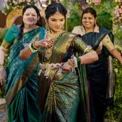 A joyful dance at a baby shower. The mom-to-be is wearing our custom floral armlets (bajuband) and a floral waist belt (kamarbandh) that beautifully accentuates her green Kanjivaram saree.