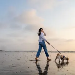 A quiet walk on the beach at sunset with your best friend. This beautiful, reflective moment between a woman and her dog shows the peaceful side of outdoor photography. The golden light and wet sand create a stunning natural backdrop.
