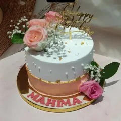 A lovely birthday cake with a two-tone rose gold and white finish. It's adorned with fresh-looking sugar roses and baby's breath for a touch of natural beauty.