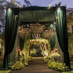 The entrance to this engagement party was designed as a grand reveal. Emerald green velvet drapes part to unveil a floral archway and sparkling chandeliers, offering guests a first taste of the enchanted garden theme that awaited them inside.