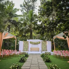 A wide view of a beautiful wedding setup on our main lawn. This shows the scale of the space, with guest seating arranged on either side of the stone aisle, all framed by towering trees.