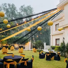 A chic black and gold themed outdoor lounge setup for a cocktail party, with draped fabrics and hanging paper lanterns.