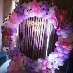 This full balloon ring in shades of pink and purple is perfect for a baby girl's shower. I added fun foil balloons like a baby bottle and a tiny foot, along with a 'Welcome baby' neon sign.