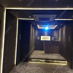 This wide shot displays the full integration of our systems. It shows the raised seating platform for clear sightlines, discreetly placed speakers, a ceiling-mounted projector, and integrated room lighting.
