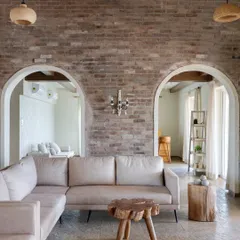 In our Alibaug villa project, 'Ekaant', we used an exposed brick wall, arched doorways, and custom log-wood tables to create an earthy, rustic feel. The design is inspired by the Indian countryside and Balinese aesthetic, focusing on natural materials and organic shapes for a tranquil getaway.