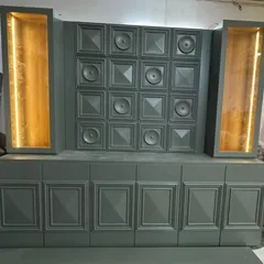A custom bar and display unit designed for a commercial space, featuring intricate paneling and integrated warm lighting. The gold leaf interior of the display niches was specifically chosen to create a radiant glow, highlighting the products on display.