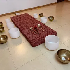 This is a classic setup for a personal sound therapy session. A comfortable mat is surrounded by a combination of Tibetan and crystal singing bowls, ready to be placed on or around the body for deep vibrational healing.