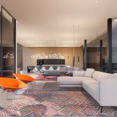 The interior of a minimalist farmhouse, designed with a steel structure to create simple, expansive spaces that hover over the site. The open-plan living area is defined by floor-to-ceiling glass, allowing the uninterrupted landscape to become the primary focus.