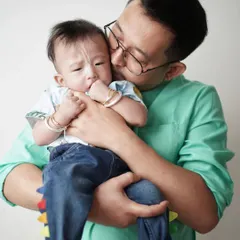 A father's gentle kiss on his baby's cheek. This tender moment, captured up close, shows the deep affection and protective love of a parent.