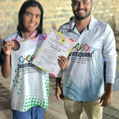 Prachita Deb celebrates her double bronze medal win in the 100m and 200m Butterfly events at the NRJ State Aquatics Championship, holding her certificate of achievement.