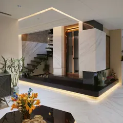 A sneak peek into a penthouse we designed, featuring a central design element that incorporates a private lift, a spiral staircase, and an indoor water body. The combination of white marble, dark wood, and strategic under-lighting creates a striking focal point.