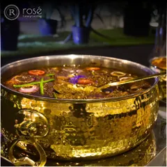 A close-up of a rich, dark curry in a hammered gold-tone bowl. We specialize in a wide range of Indian main courses, each prepared with authentic spices and slow-cooking techniques.