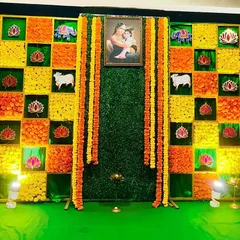 This backdrop features a vibrant checkerboard pattern made from marigolds and other traditional flowers. A central portrait of Yashoda and Krishna adds a divine touch, perfect for a Seemantham ceremony.
