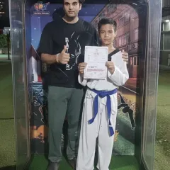 A student proudly displays his certificate after a successful belt grading. Each new belt is a milestone on the journey to black belt.