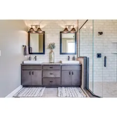 A classic bathroom with a double vanity, perfect for shared spaces. The design features a subway tile walk-in shower, dark wood cabinets, and elegant lighting fixtures above each mirror.