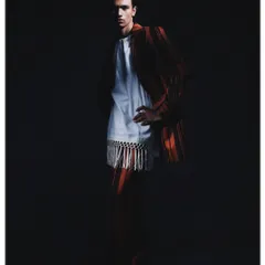 A classic portrait pose from the 'Silhouette' series, with the model standing against a dark background. The lighting is carefully controlled to highlight the contours of the suit and the subject's form.